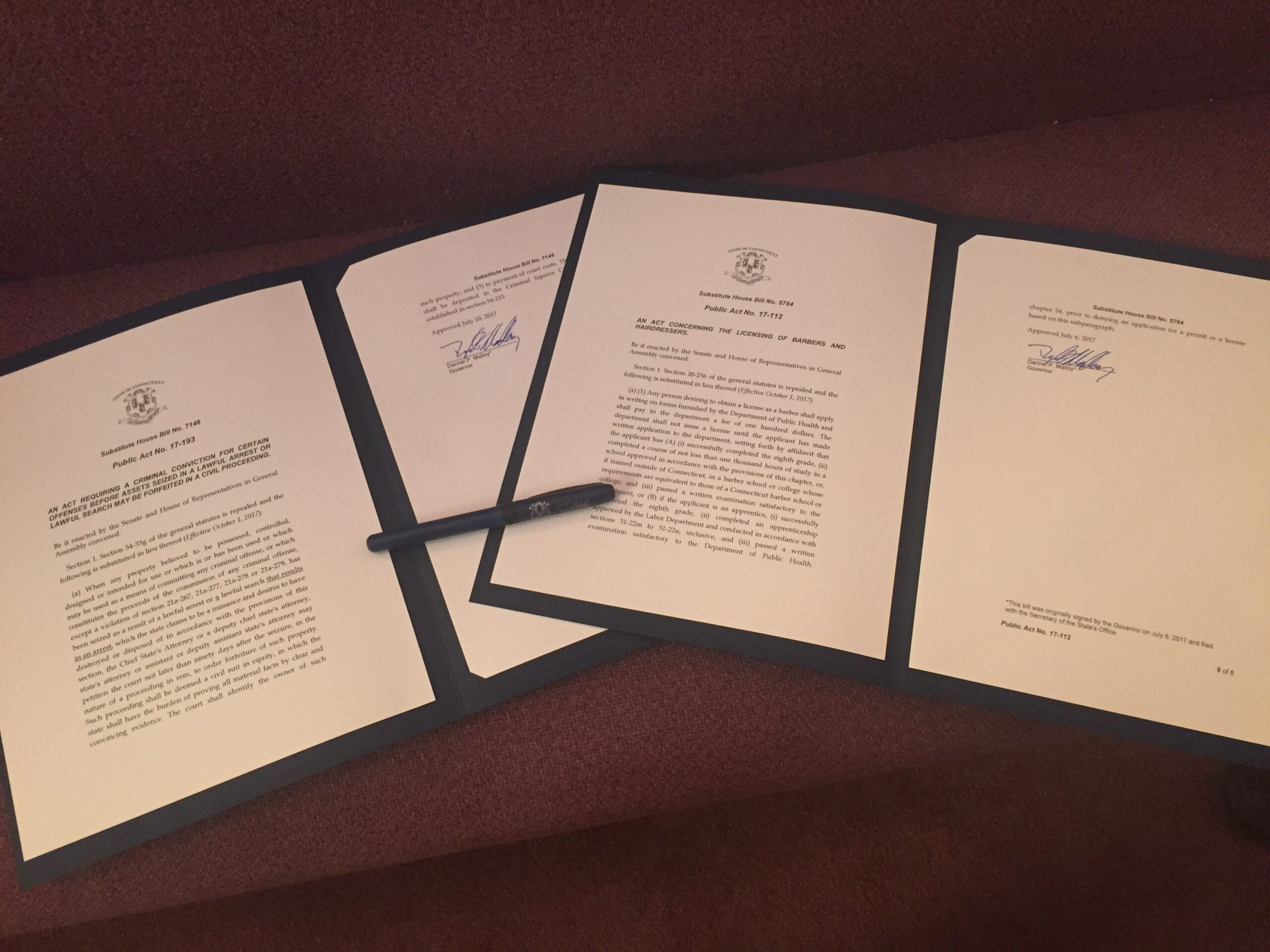 Ceremonial copies of Connecticut's 2017 civil asset forfeiture reform and fair chance licensure for babers and hairdressers laws