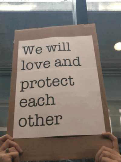 We will love and protect each other sign at Bradley Airport protest against Trump Administration's Muslim ban