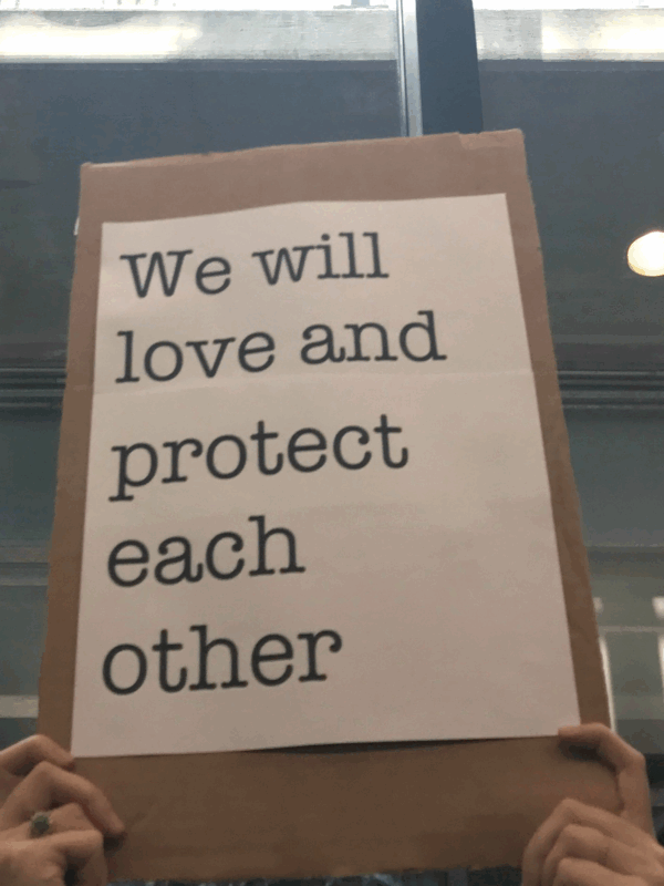 We will love and protect each other sign at Bradley Airport protest against Trump Administration's Muslim ban