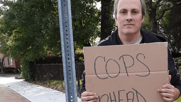 ACLU of Connecticut client protester Michael Friend holds "cops ahead" sign in Stamford