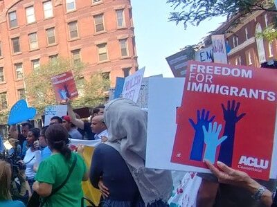 Photo of crowd at Hartford rally, including red ACLU of Connecticut sign that says "freedom for immigrants"