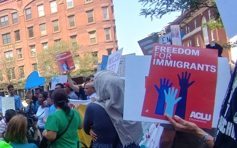 Photo of crowd at Hartford rally, including red ACLU of Connecticut sign that says "freedom for immigrants"
