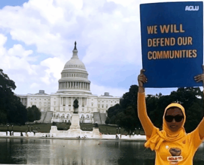 Rowanne Mustafa poses with "We will defend our communities" ACLU poster outside of the U.S. Capitol Building