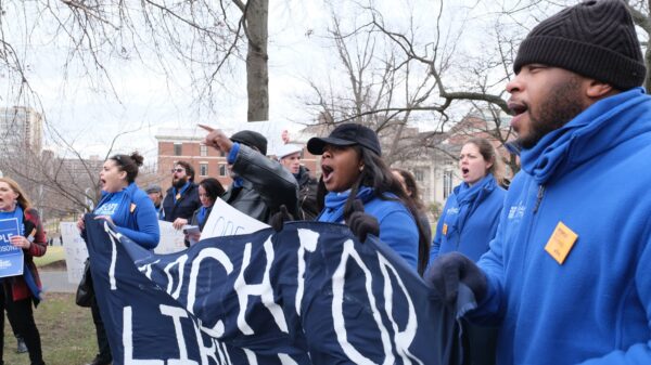 ACLU-CT Smart Justice leaders, in blue fleeces, stand side by side holding a "March for Liberation" banner. They are joining a chant.
