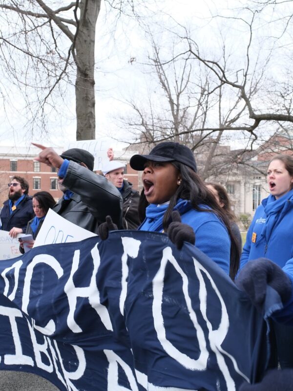 ACLU-CT Smart Justice leaders, in blue fleeces, stand side by side holding a "March for Liberation" banner. They are joining a chant.