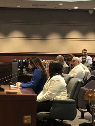 Ciara Rosati, Smart Justice leader, testifies in support of strong Clean Slate, SB 403, at the CT General Assembly in 2020. Ciara wears a blue shirt and is seated next to policy counsel Kelly Moore, in a white blazer.