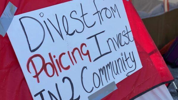 Red tent with white sign. Sign reads: Divest from policing / invest in2 community