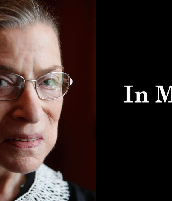 A close up photo of Supreme Court Justice Ruth Bader Ginsburg is on the left. She is looking directly at the camera. On the right, a black box. In the box, "in memory" is written in white letters.