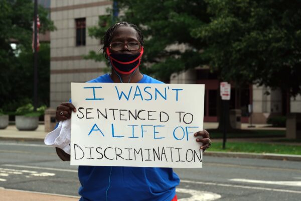 ACLU-CT Smart Justice leader stands with sign: I wasn't sentenced to a life of discrimination