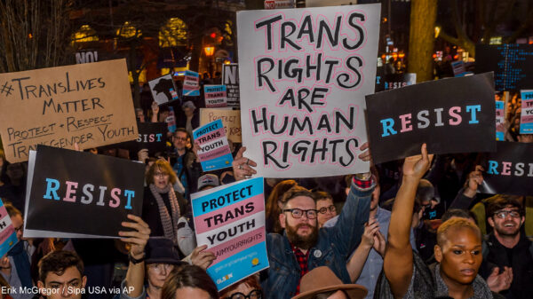 Protestors with signs advocating for the rights of trans youth.