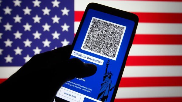 In this photo illustration, Excelsior Pass app which provides digital proof of COVID-19 vaccination or negative test results seen displayed on a smartphone screen in front of the US flag.