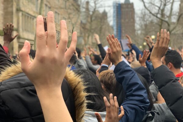 Photo of people with hands raised.
