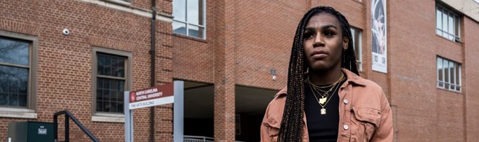 Andraya Yearwood stands in a blush jacket and braids in front of a brick building. Photo credit Steve Resich ACLU