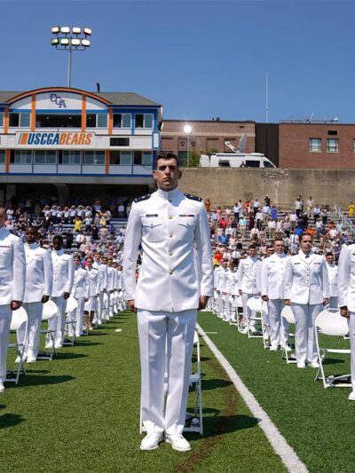 US Coast Guard cadets in white uniforms stand in neat rows at the commencement for the United States Coast Guard Academy in New London, Conn.