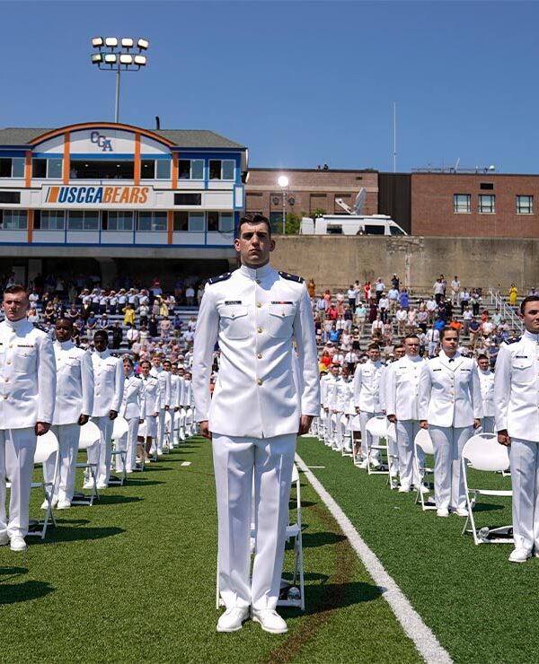 US Coast Guard cadets in white uniforms stand in neat rows at the commencement for the United States Coast Guard Academy in New London, Conn.
