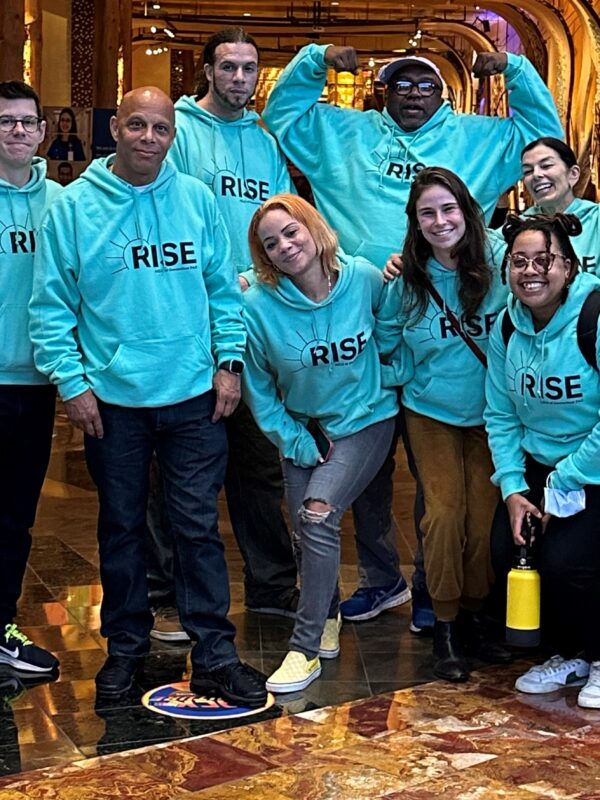 Group of individuals wearing green Rise PAC sweatshirts
