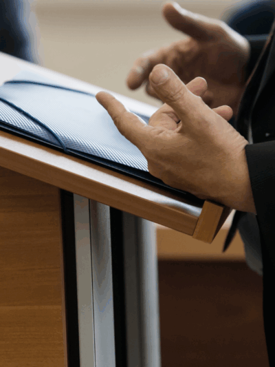 an individual standing at a podium speaking, only their hands and the podium are visable