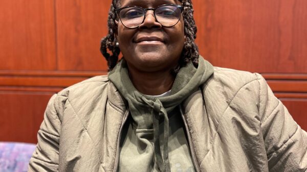 ACLU CT Smart Justice leader Terri Ricks sits, smiling at the camera and wearing a brown jacket and brown hoodie.