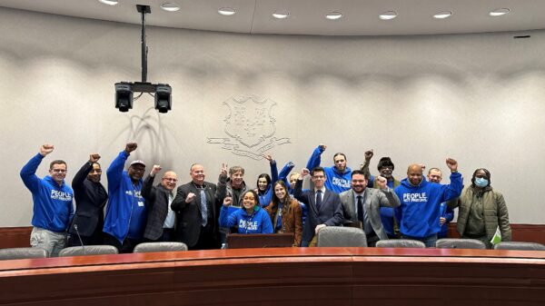 innocence project and acluct smart justice gather for press conference combatting police deception, all are standing or crouching, smiling, with fists raised