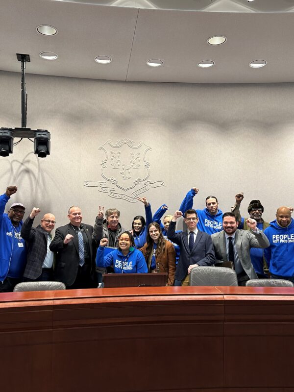 innocence project and acluct smart justice gather for press conference combatting police deception, all are standing or crouching, smiling, with fists raised