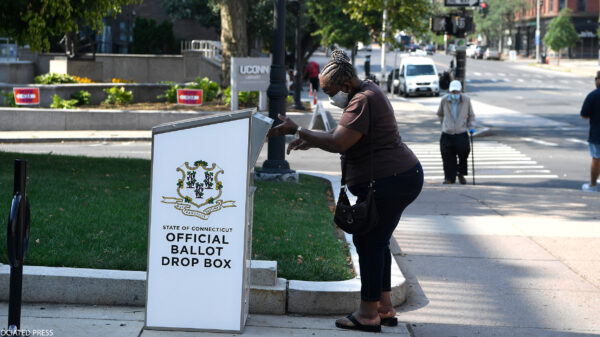 An Afrian-American woman drops a ballot into a State of Connecticut Official Ballot Drop Box outside Hartford City Hall.