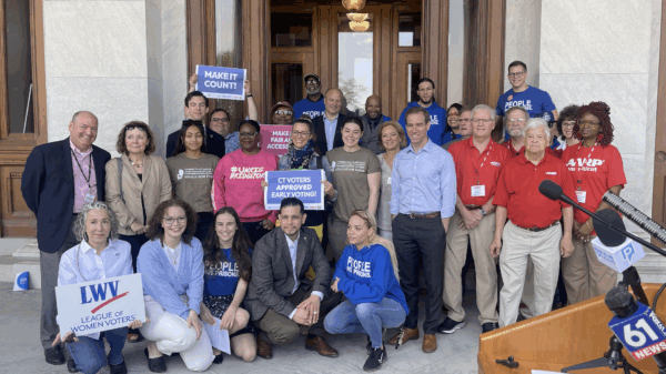 ACLU-CT staff and partners are posing in front of the camera with signs to promote the CTVRA.