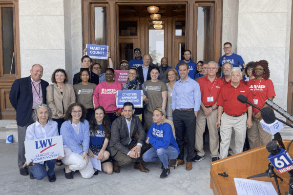 ACLU-CT staff and partners are posing in front of the camera with signs to promote the CTVRA.
