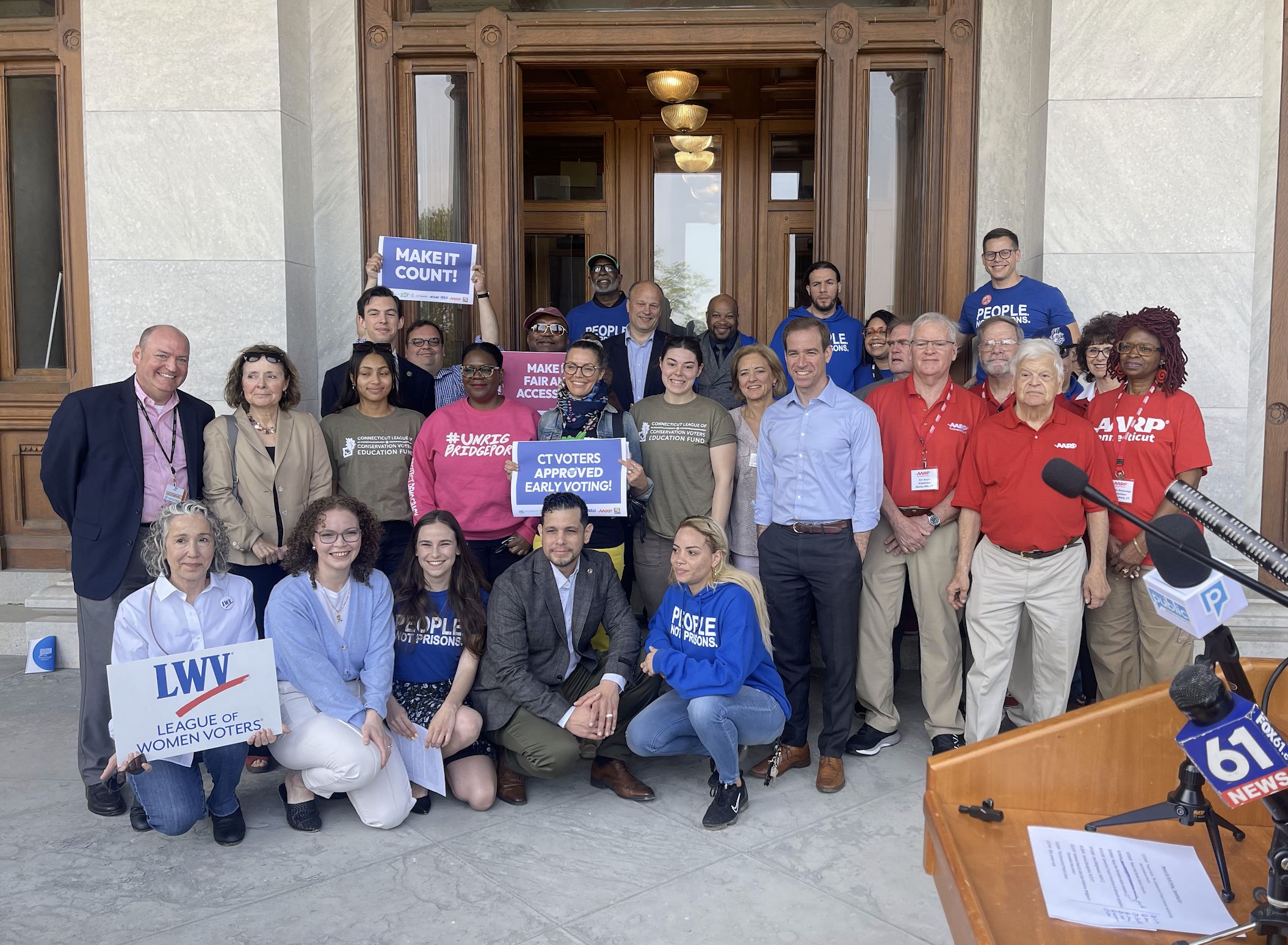 ACLU-CT staff and partners are posing in front of the camera with signs to promote the CTVRA.