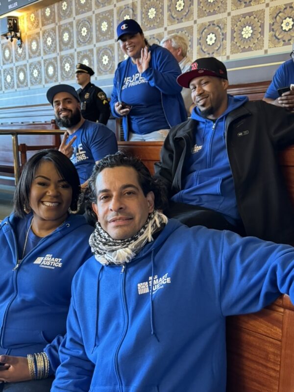 Six Smart Justice leaders sit in the senate room smiling at the camera.