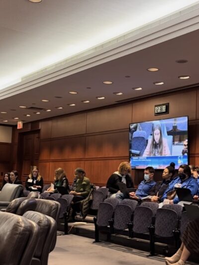 Jess, policy counsel, sits in front of the housing committee testifying in support of HB5242 with Smart Justice leaders behind her.