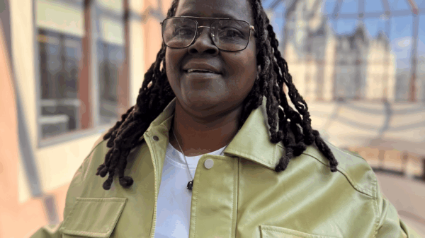 Terri, one of our Smart Justice Leaders, is a Black woman wearing a yellow leather jacket with her hair in a protective style (locs) and black wire rim glasses.