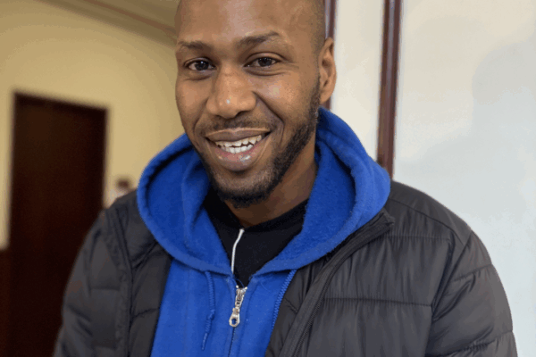 Chris, a Smart Justice Leader, is smiling at the camera wearing one of the smart justice zip ups.