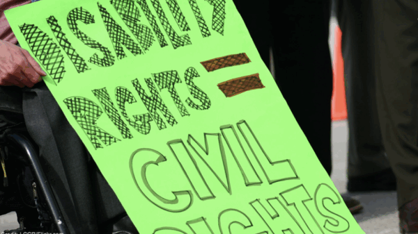The focus of this image is a neon green sign that reads "Disability rights = Civil rights."