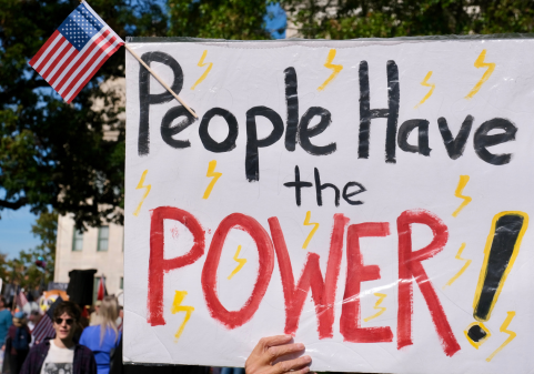 A white poster sign that reads the following in black: "People have the POWER" with little lightning bolts drawn randomly around the sign.