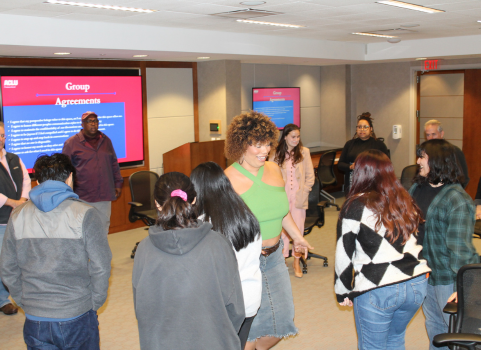With several other people in a circle, our field organizer Erycka stands in the middle of a circle in a bright green shirt and a jean skirt while talking and laughing with supporters.