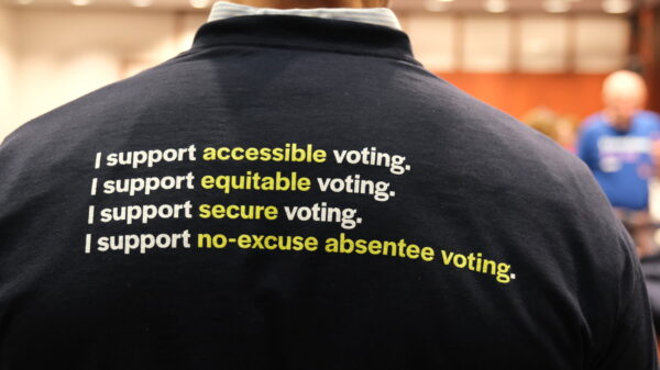 The back of Gus' shirt is navy blue and reads "I support accessible voting. I support equitable voting. I support secure voting. I support no-excuse absentee voting." in white.