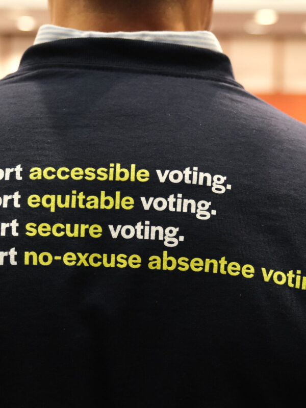 The back of Gus' shirt is navy blue and reads "I support accessible voting. I support equitable voting. I support secure voting. I support no-excuse absentee voting." in white.