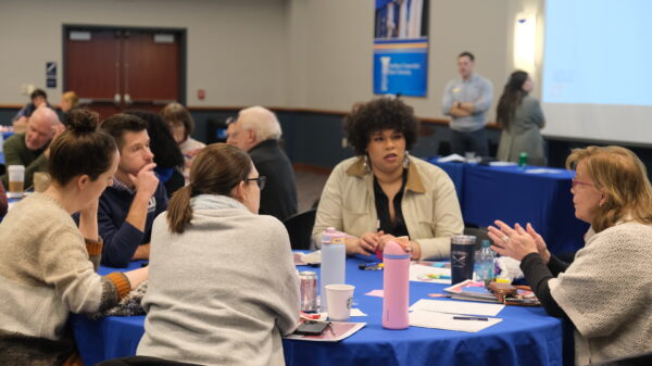 ACLU staff are sitting around a blue circular table and are candidly talking with one another.
