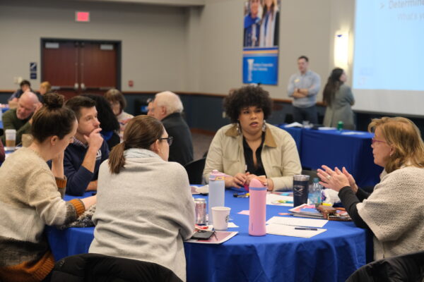 ACLU staff are sitting around a blue circular table and are candidly talking with one another.
