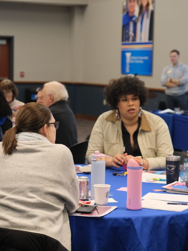 ACLU staff are sitting around a blue circular table and are candidly talking with one another.