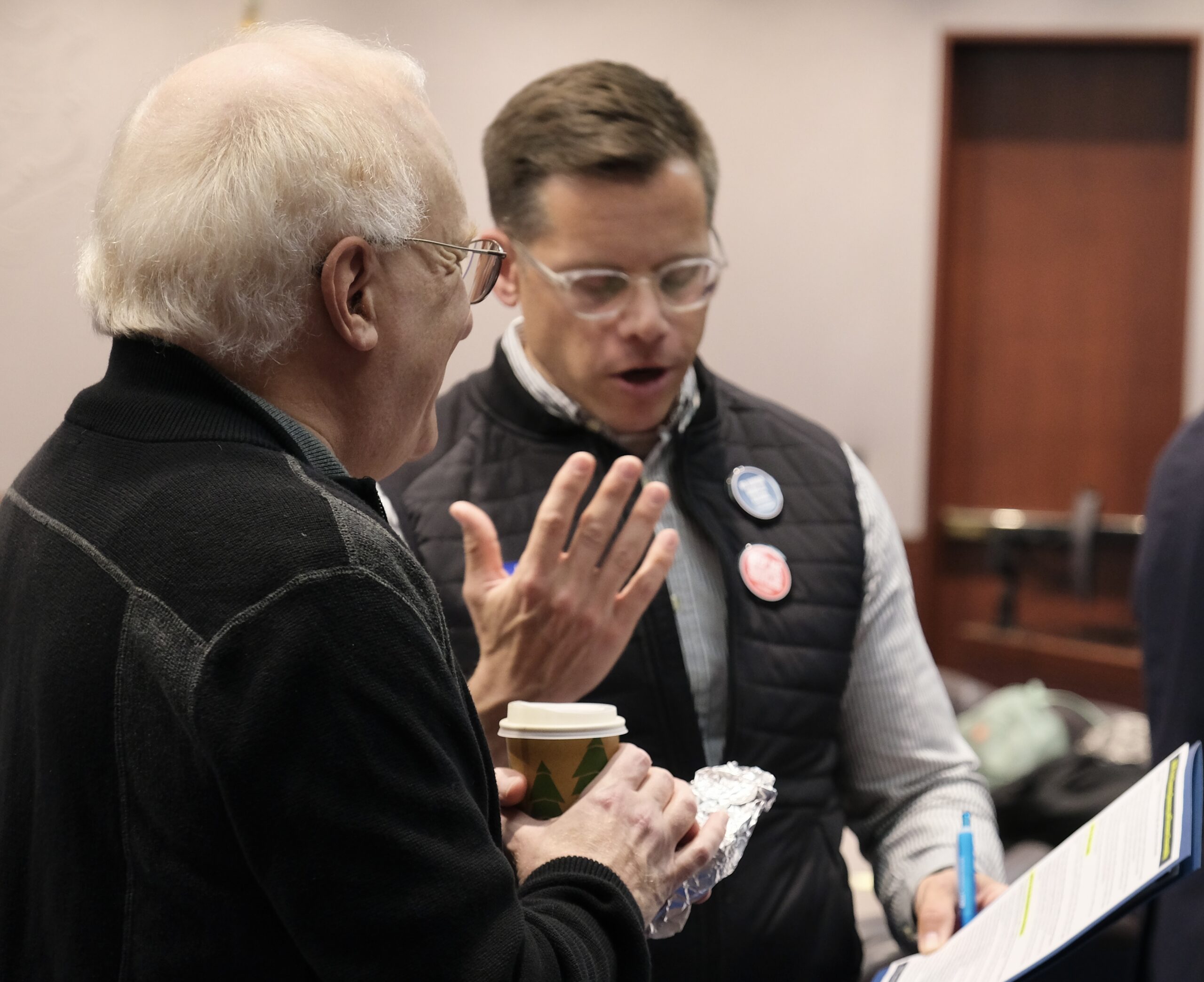Gus and a volunteer are talking to get ready for a lobby day. They are reviewing the fact sheet for a bill together in the frame.