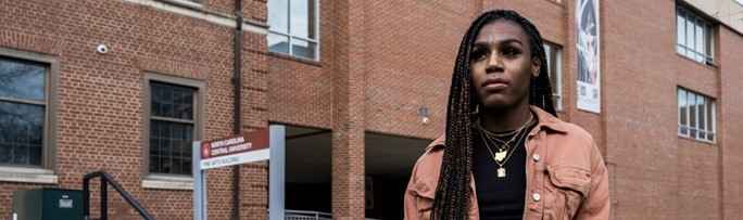 Andraya Yearwood stands in a blush jacket and braids in front of a brick building. Photo credit Steve Resich ACLU