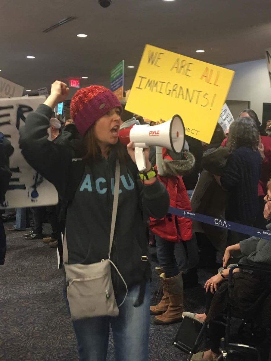 A woman in an ACLU shirt protests against the Trump Administration's Muslim Ban at Bradley Airport in Connecticut