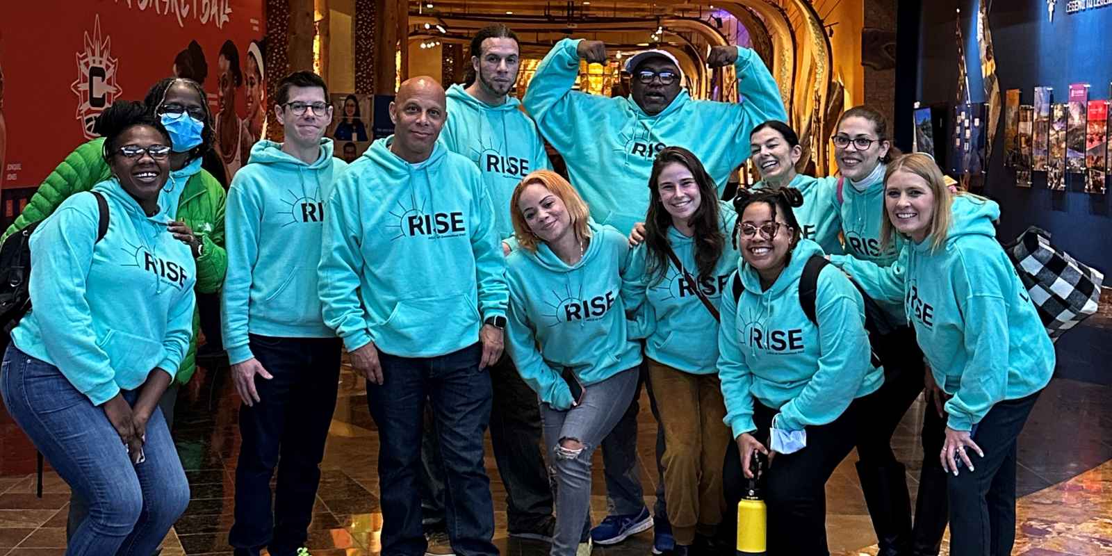 Group of individuals wearing green Rise PAC sweatshirts