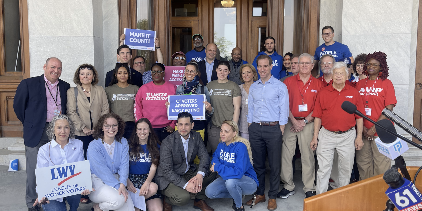 ACLU-CT staff and partners are posing in front of the camera with signs to promote the CTVRA.