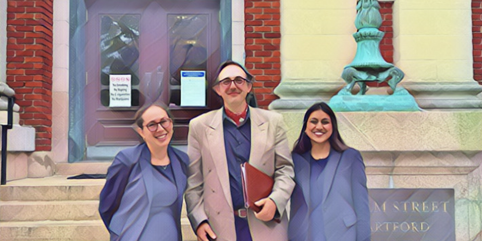 Our Senior Staff Attorney and our Legal Fellow stands in front of the appellate court house with one of our clients.