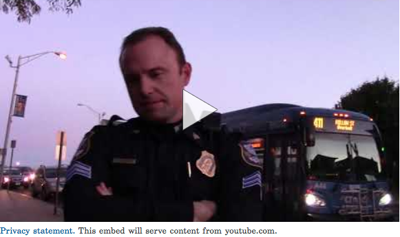 Screen shot of Massimino video. Waterbury police employee can be seen. City bus in the background.