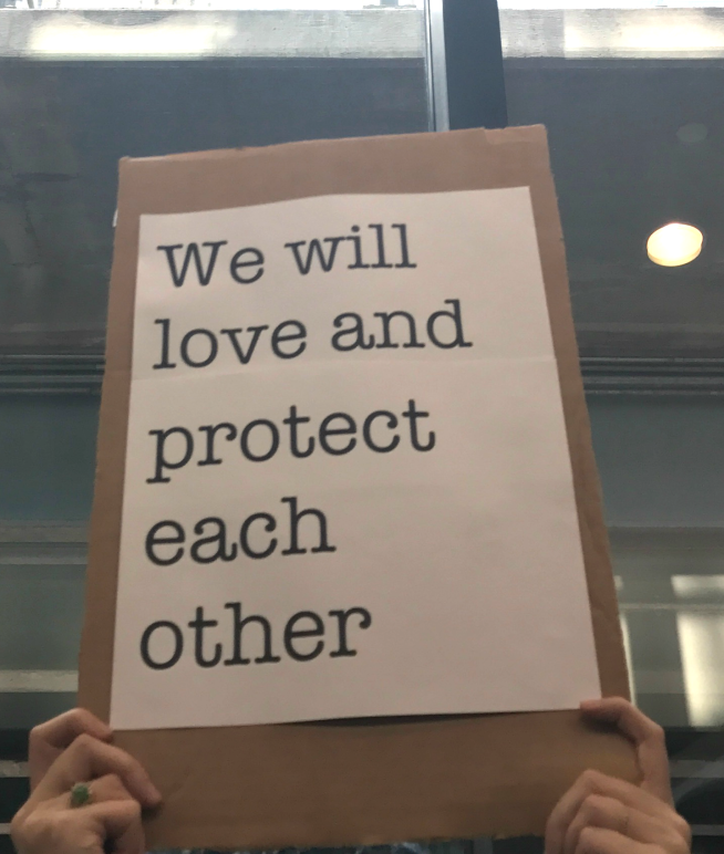 We will love and protect each other sign at Bradley Airport protest against Trump Administration's Muslim ban