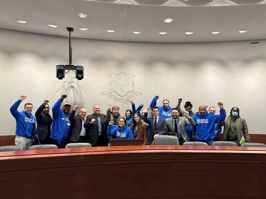innocence project and acluct smart justice gather for press conference combatting police deception, all are standing or crouching, smiling, with fists raised