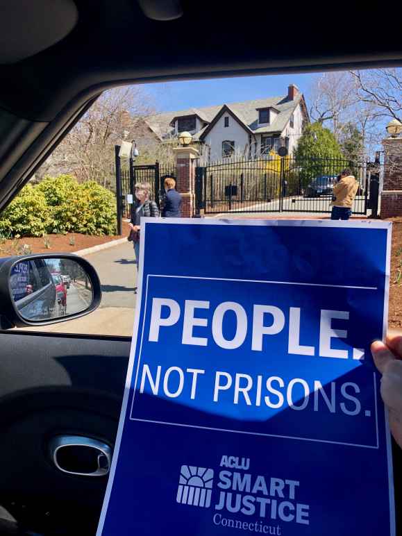 blue aclu of connecticut people not prisons poster in front of Connecticut governor's mansion
